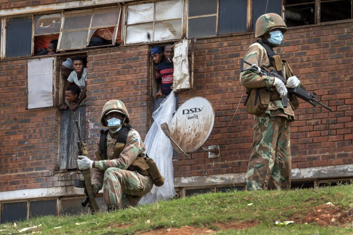 South African National Defense Forces patrol a men's hostel in the densely populated Alexandra township east of Johannesburg, Saturday, March 28, 2020, enforcing a strict lockdown in an effort to control the spread of the coronavirus. Responding quickly with one of the world’s harshest lockdowns, South Africa slowed the initial spread of the coronavirus and the country passed its first peak with far less deaths than experts had predicted. (AP Photo/Jerome Delay)