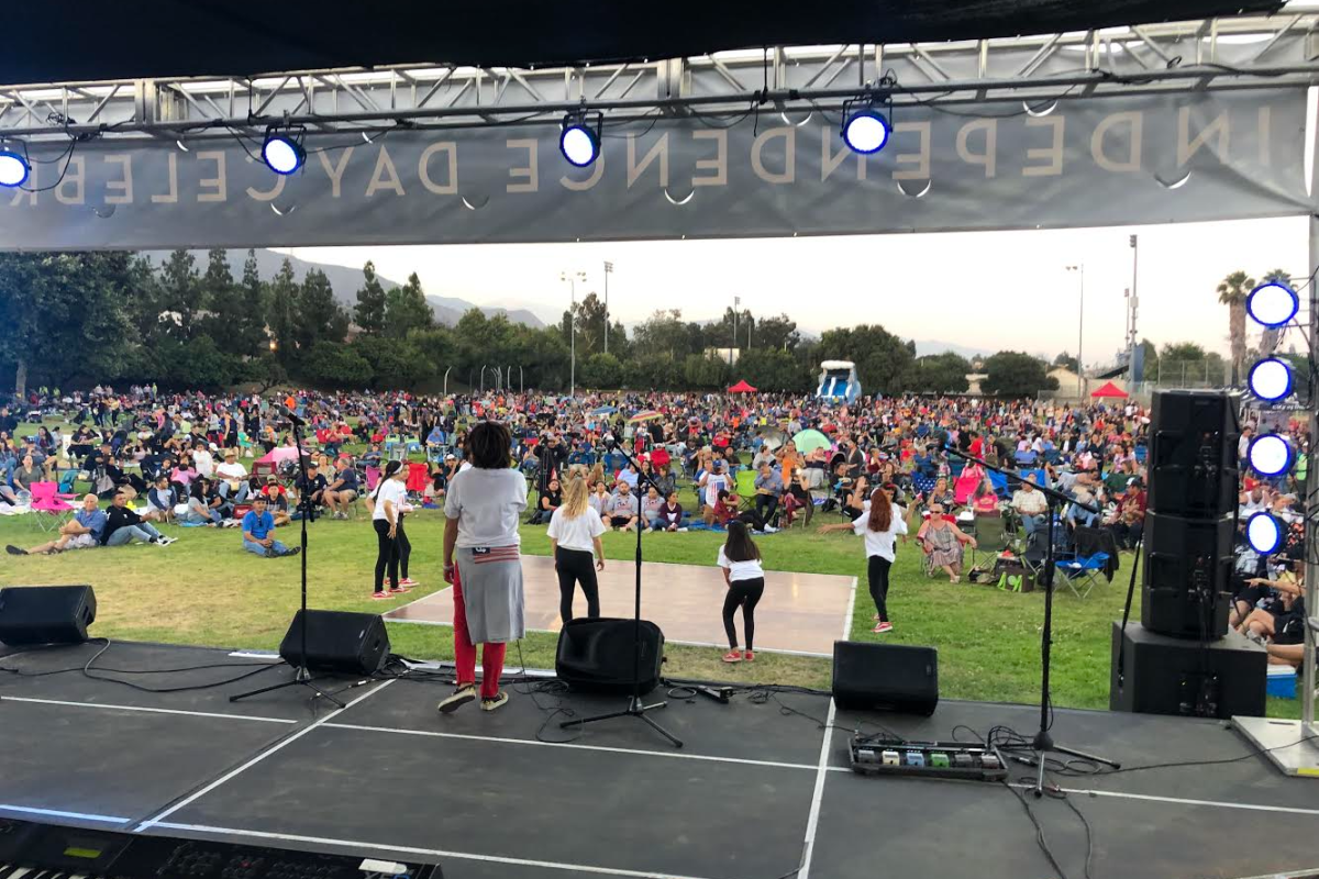 A photo taken from a stage looking out onto five performers in front of a large crowd