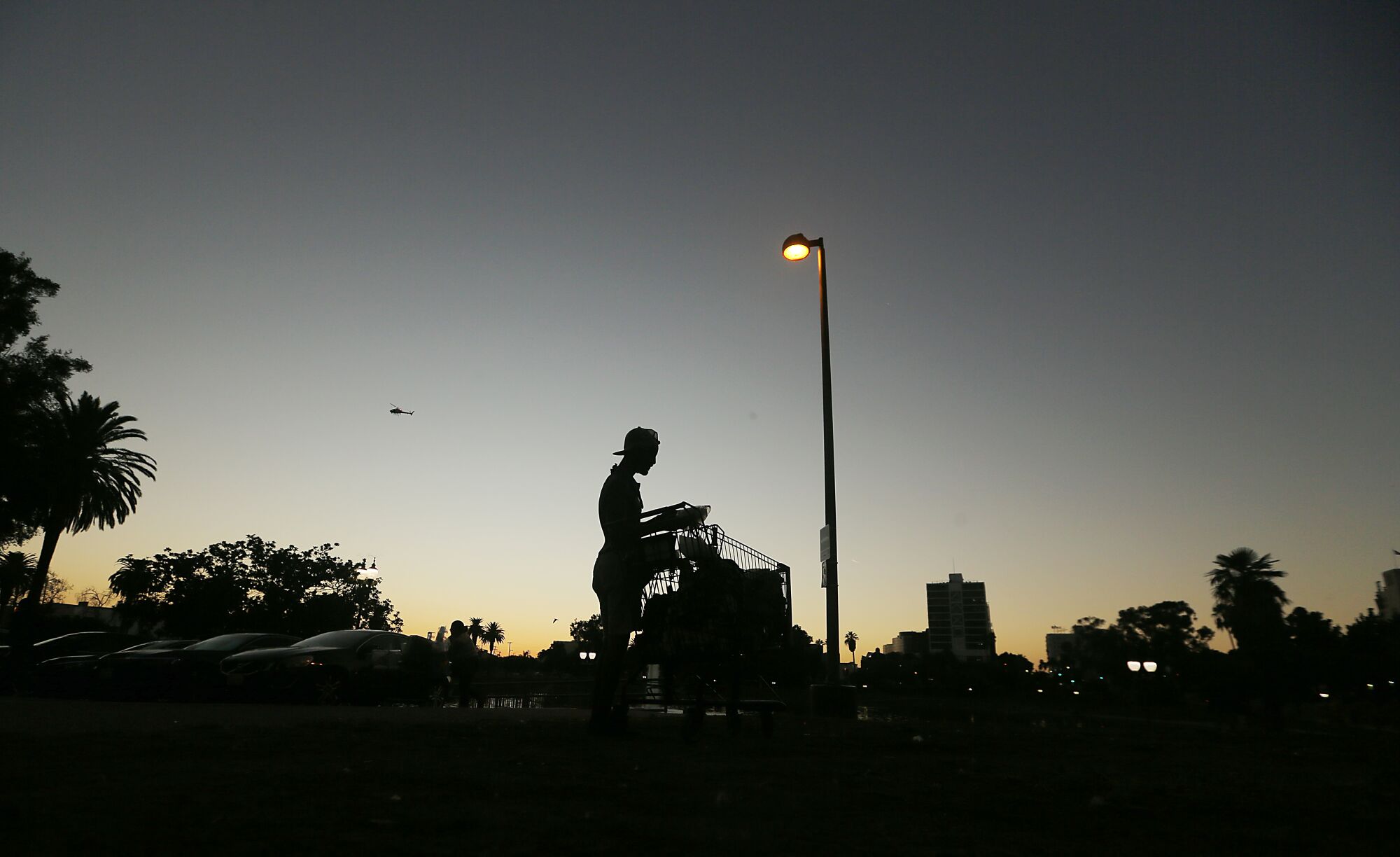 A homeless man collects his belongings before leaving MacArthur Park in Los Angeles