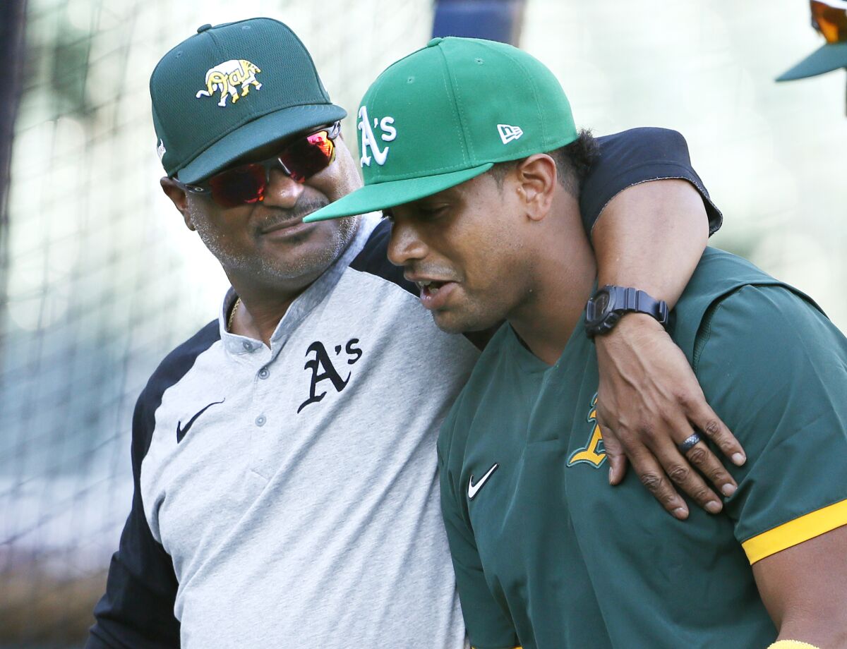 Oakland Athletics assistant hitting coach Eric Martins puts his arm around Khris Davis, right, as they leave the field following batting practice for the team's baseball game against the Detroit Tigers on Wednesday, Sept. 1, 2021, in Detroit. Davis was called up from Triple-A affiliate in Las Vegas for the September roster expansion. (AP Photo/Duane Burleson)