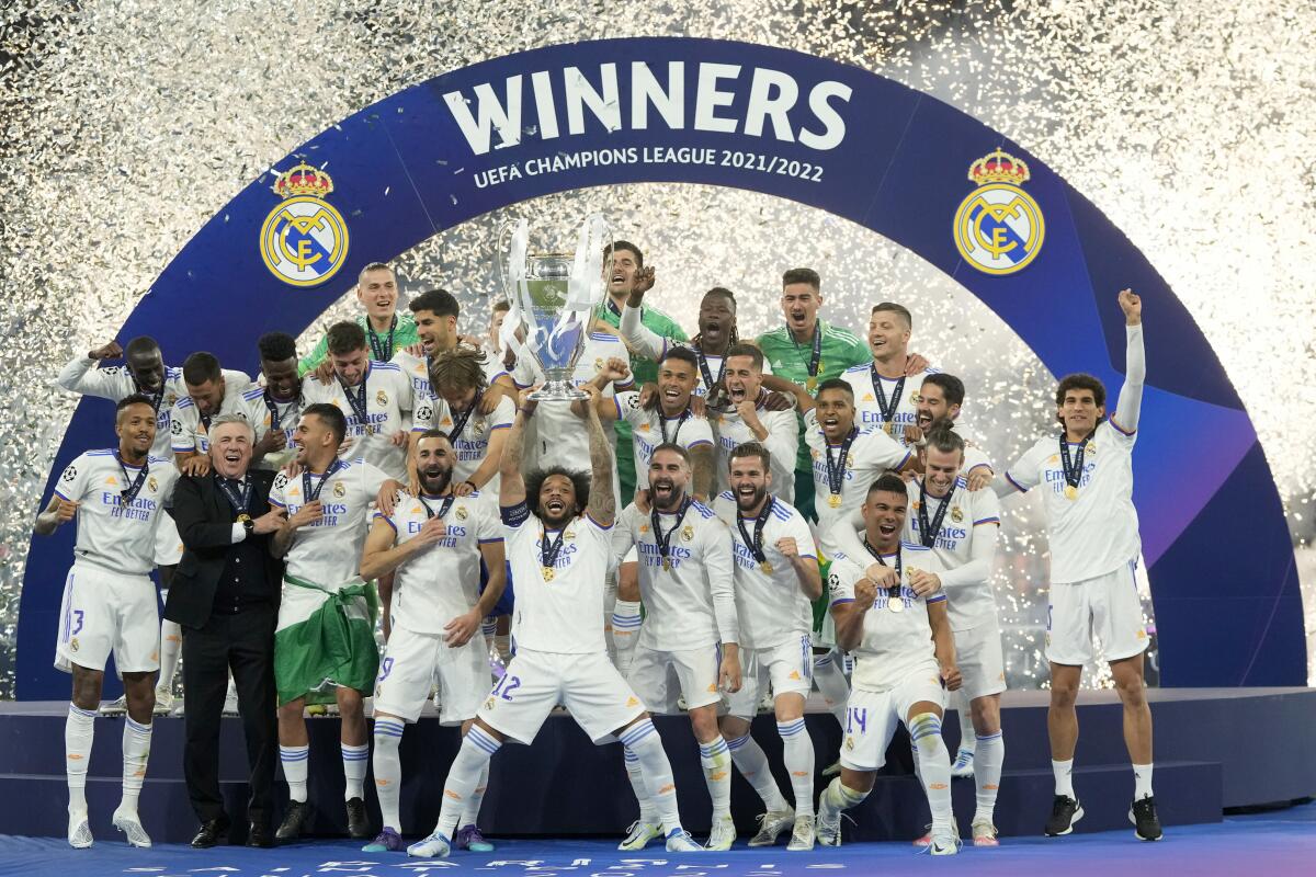 Real Madrid's Marcelo lifts the trophy after winning the Champions League final soccer while teammates stand near him.