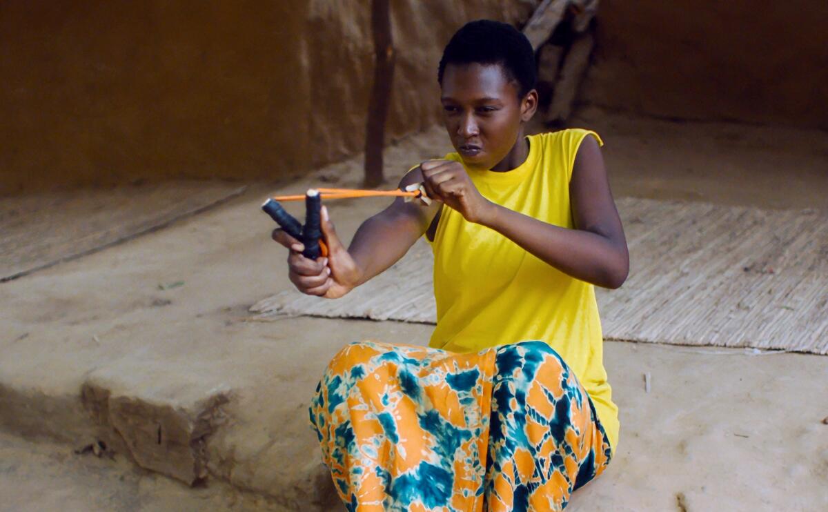 woman in yellow shirt pulls back a slingshot