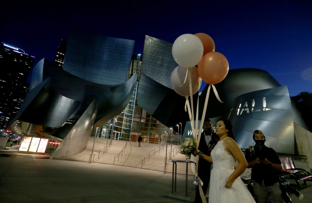 Coronavirus has turned once-bustling downtown L.A. into a
ghost town. Can it recover? 6 Newlyweds have their picture taken at the Walt Disney Concert Hall in downtown Los Angeles.