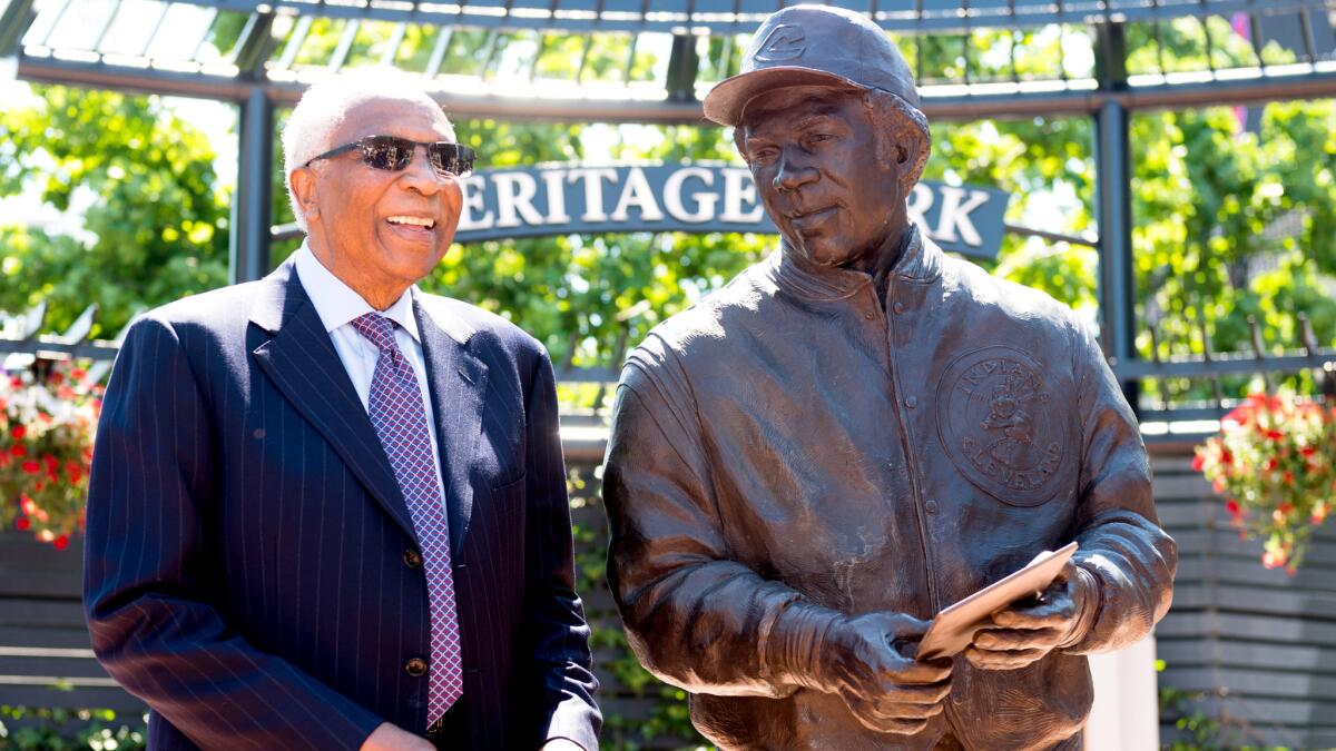 Former Cleveland Indians manager and player Frank Robinson stands next to new statue commemorating his career four decades after he became the first African-American manager in the majors.