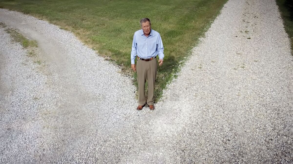 Republican former Ohio Gov. John Kasich stands at a gravel crossroads in a Democratic National Convention video
