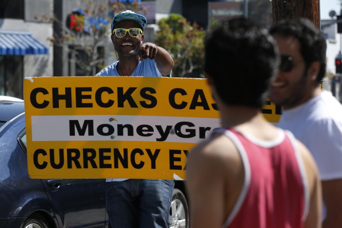 Sign spinner David Harwell grabs attention by dancing and holding an arrow-shaped cardboard sign advertising a cash checking establishment at the corner of North La Cienega Boulevard and West 3rd Street.