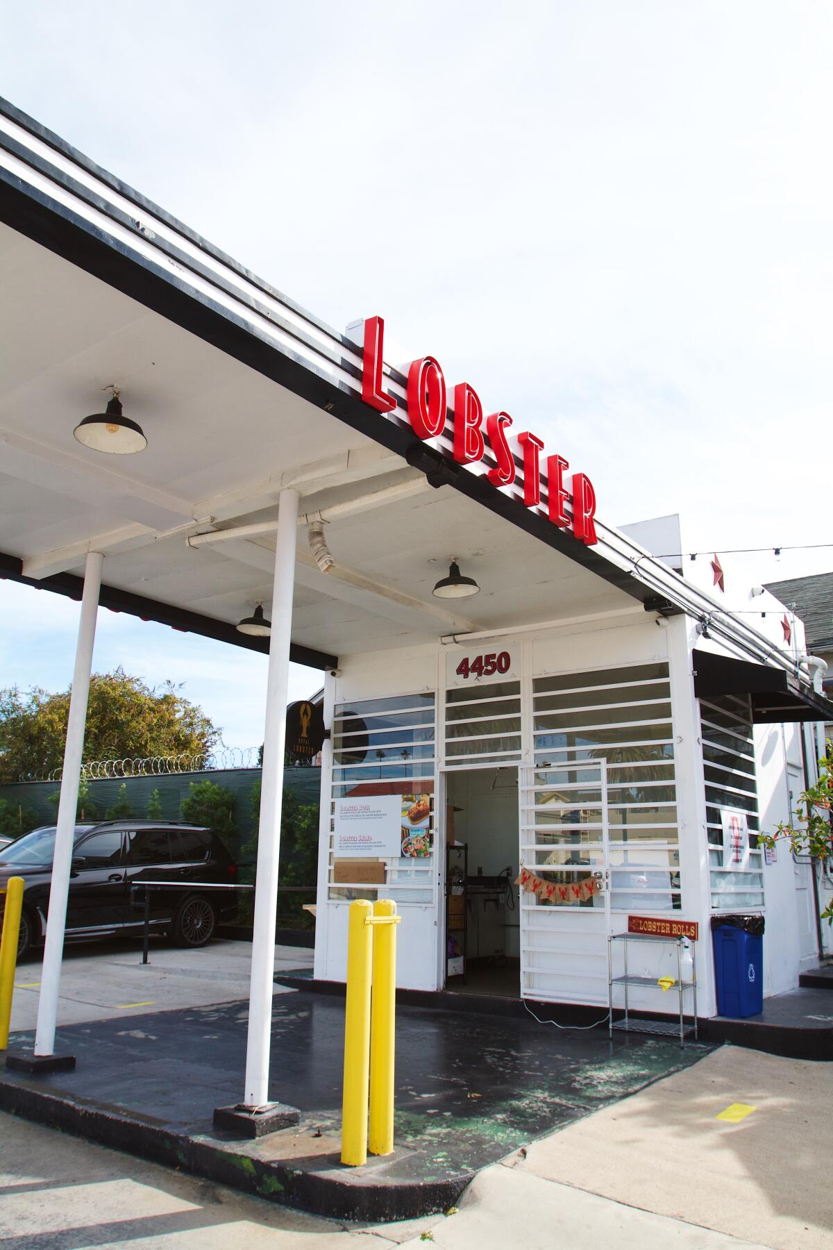 A vertical photo of the white-and-black vintage gas station of Royal Lobster with "LOBSTER" in red signage