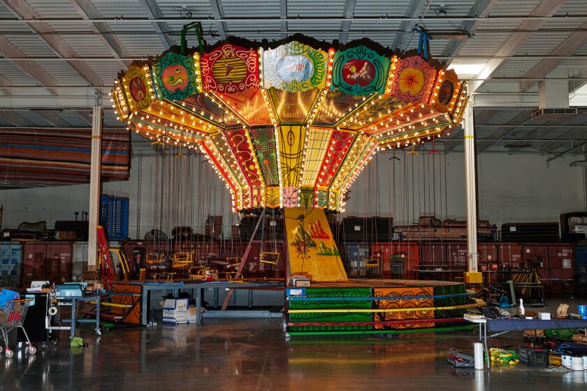 A Kenny Scharf-designed swing ride is partly lit-up in a Los Angeles warehouse. 