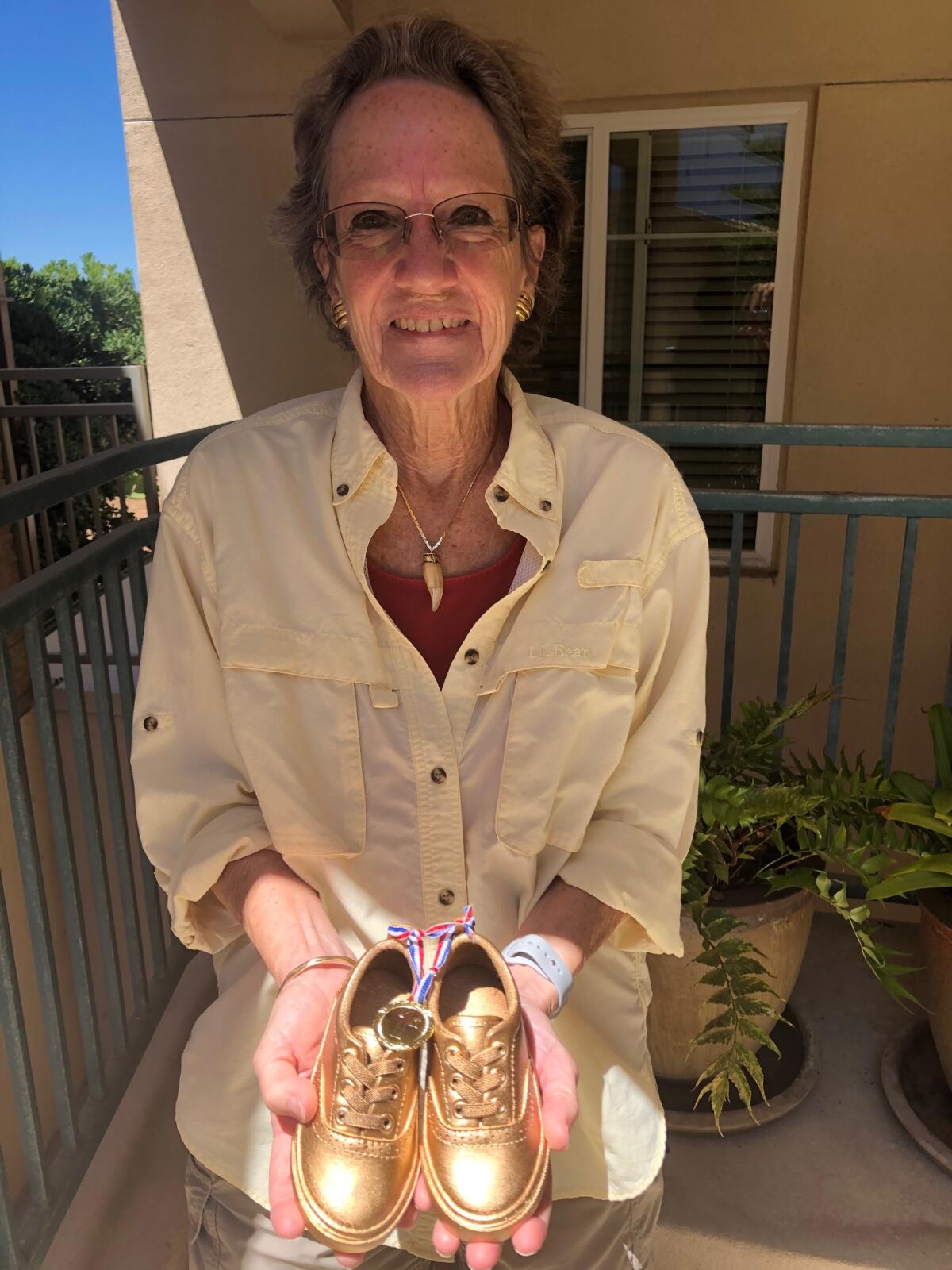 White Sands resident Anita Holmes shows the gold sneakers she received after winning the community's walking challenge.