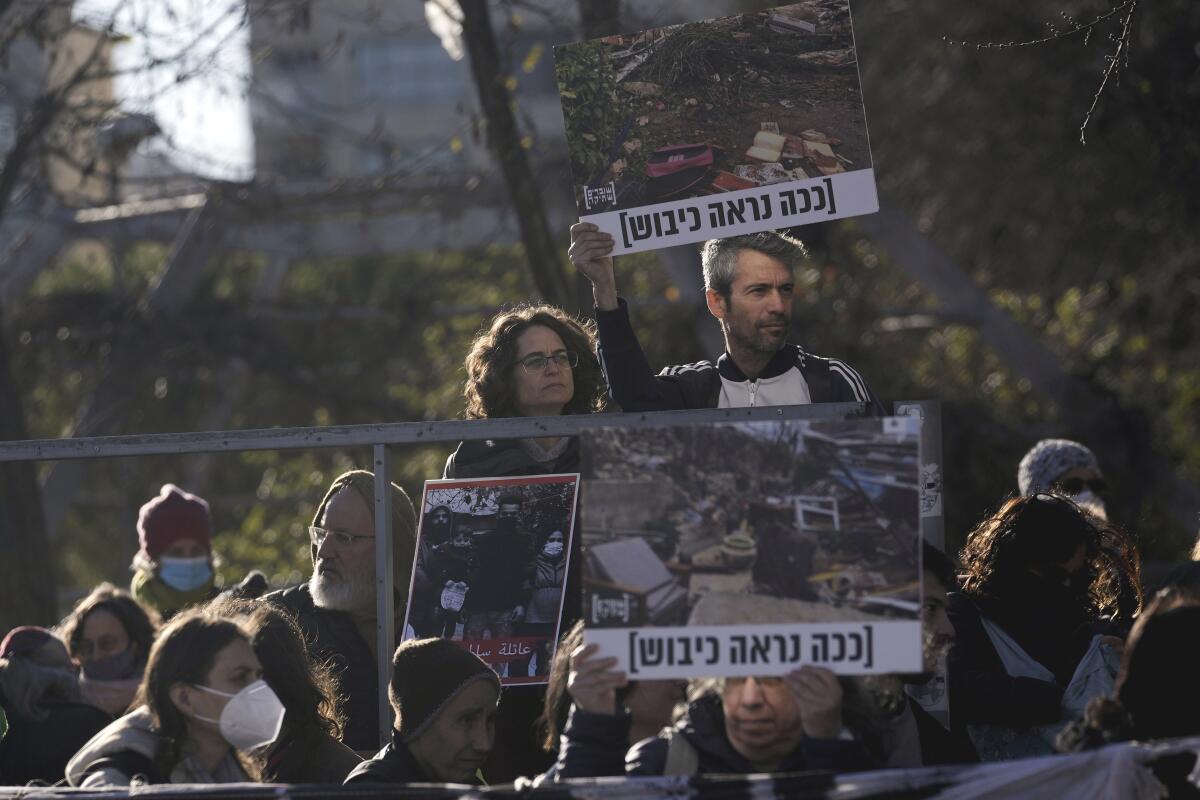 Protesters in Israel hold pictures of a demolished home