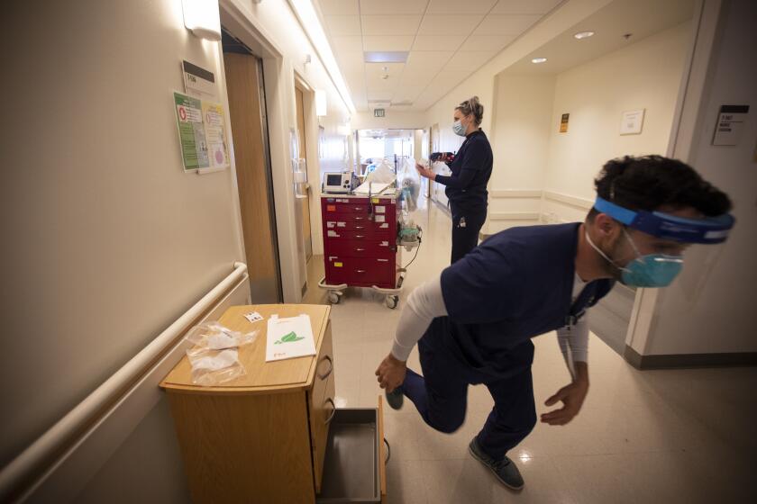 LOS ANGELES, CA - APRIL 27: During the coronavirus global pandemic Joshua Barba, (CQ) RN, right, runs during a rabid response to help a covid-19 positive patient on the COVID-19 cohort unit at Martin Luther King, Jr., Community Hospital on Thursday, April 27, 2020 in the Willowbrook neighborhood located in South Los Angeles, CA. (Francine Orr / Los Angeles Times)