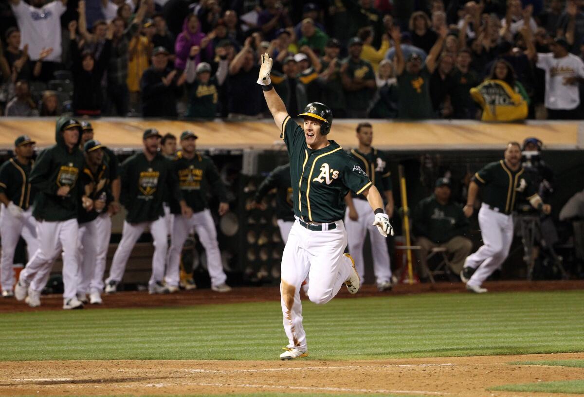 Athletics first baseman Mark Canha runs home to score the winning run on a Billy Butler double the 10th inning against the Dodgers.