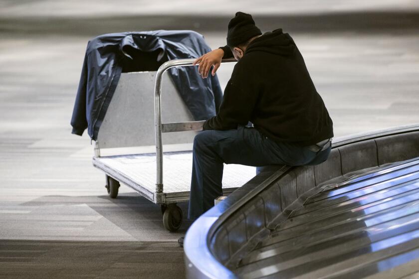 Baggage handler Mikal Hanton rests his head as he sits on a caracul at Philadelphia International Airport in Philadelphia, Thursday, March 19, 2020. A labor union says hundreds of contract workers at Philadelphia International Airport are getting laid off as flight cancellations soar because of the spreading coronavirus. (AP Photo/Matt Rourke)