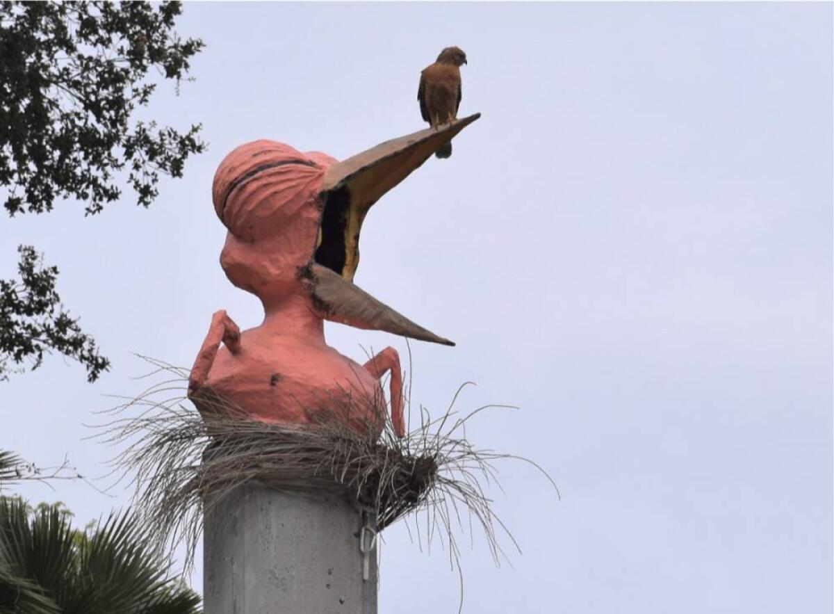 A papier-mâché bird atop a concrete pillar