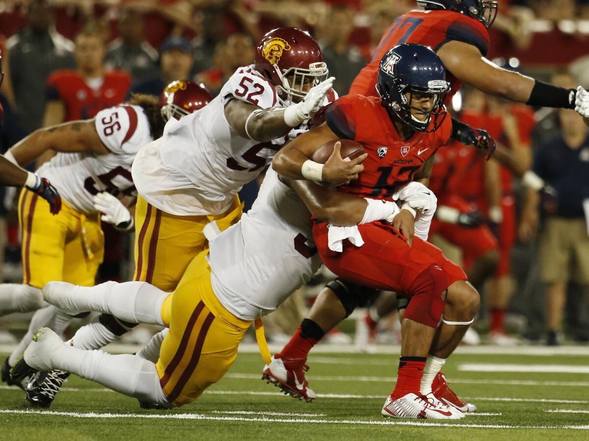 Arizona quarterback Anu Solomon, right, is sacked by USC teammates Delvon Simmons, left, and Leonard Williams during the first half of Saturday's game.