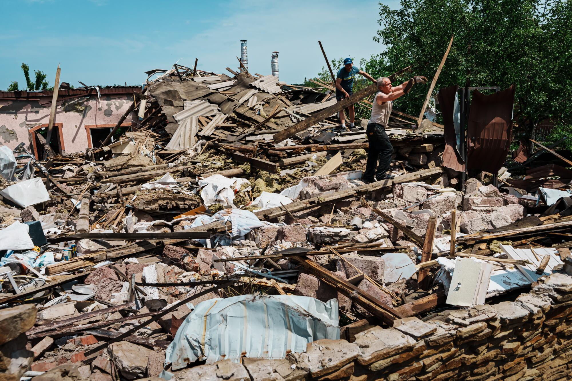 Local residents clear out debris after a bombardment destroyed a house in the outskirts of Slovyansk, Ukraine.