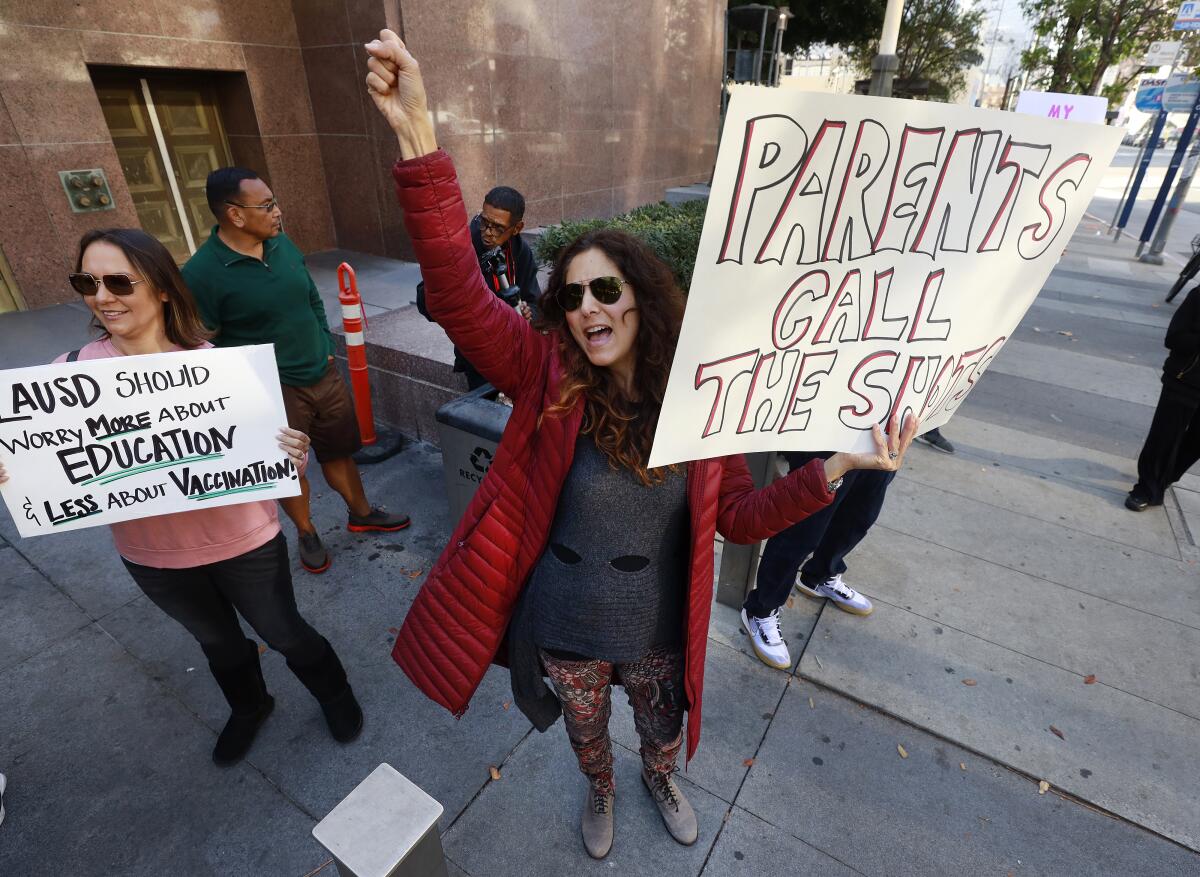 Protesters rally in downtown Los Angeles. One holds a sign that says "Parents call the shots." 
