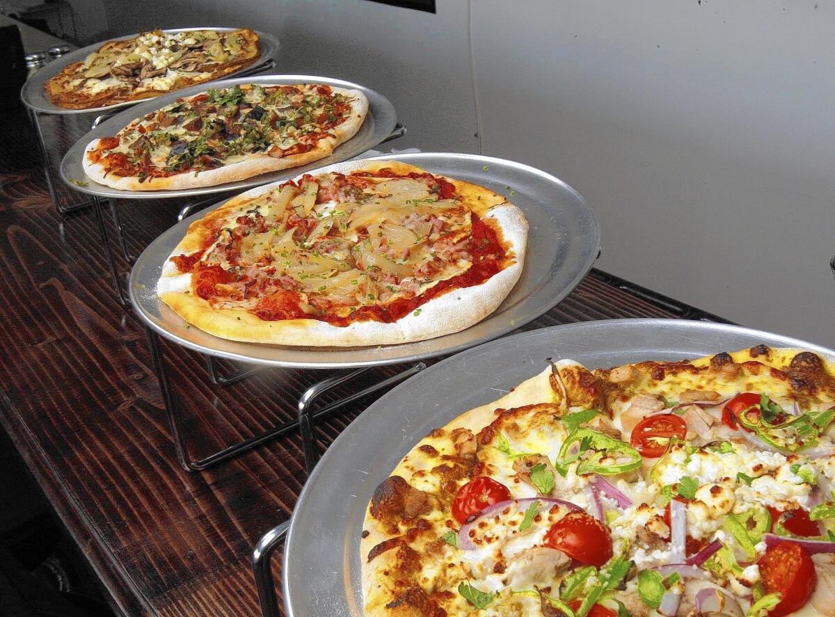 Pizzas, from right to left, are curry chicken, POV pancetta, braised lamb and gluten-free fungi at Pizza of Venice in Altadena on Wednesday, Feb. 12, 2014.
