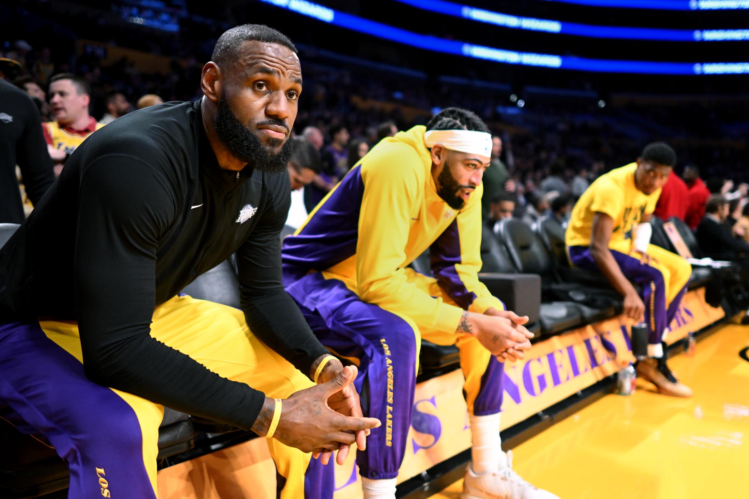 Lakers stars LeBron James, left, and Anthony Davis sit on the bench before player introductions.