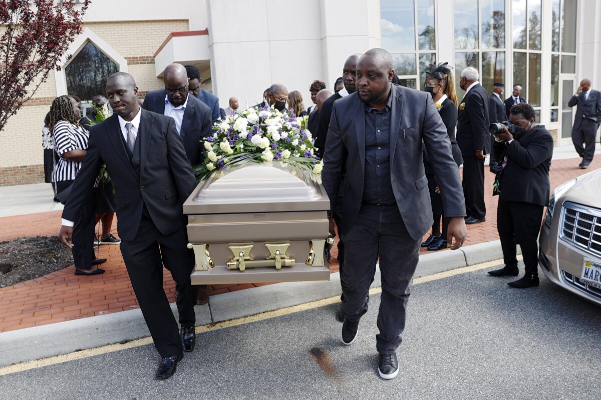 Men carrying a funeral casket across the street.