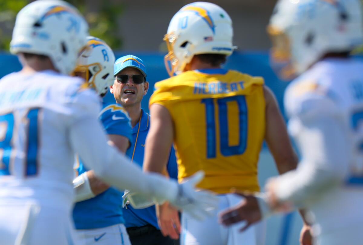 Jim Harbaugh watches as quarterback Justin Herbert approaches the Chargers coach.