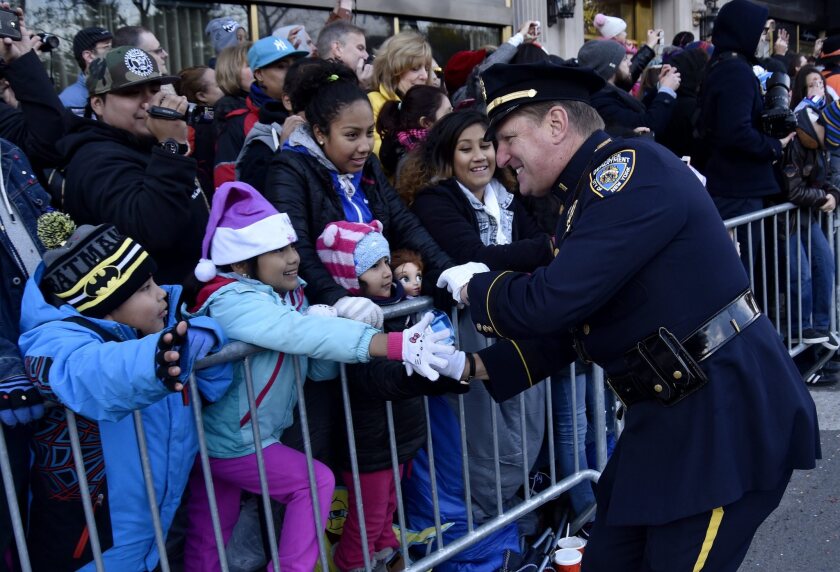 An officer marching with the NYPD Band greets spectators during the 89th Macy's Thanksgiving Day Parade in New York City on Thursday.