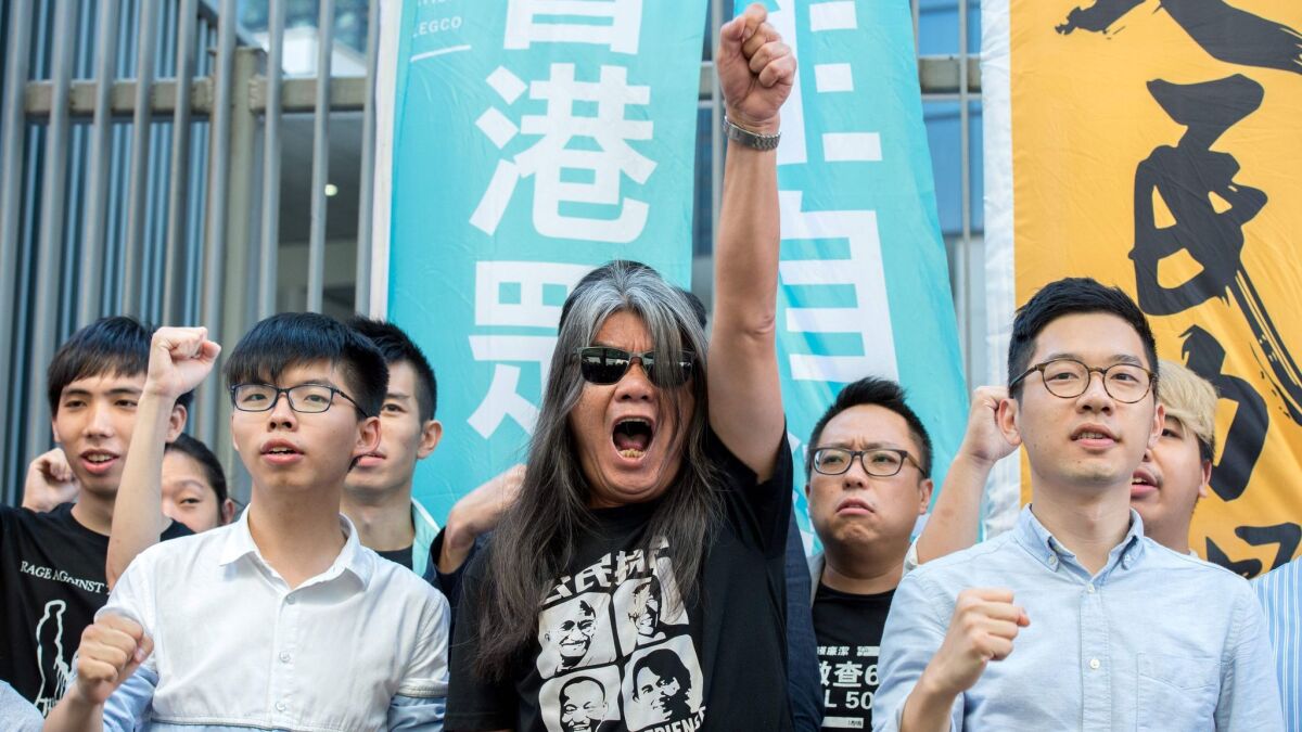 Student protest leader Joshua Wong, left; pro-democracy lawmaker Leung Kwok-hung, also known as "Long Hair"; and pro-democracy lawmaker Nathan Law protest against their recent arrests and detention in Hong Kong on Friday.