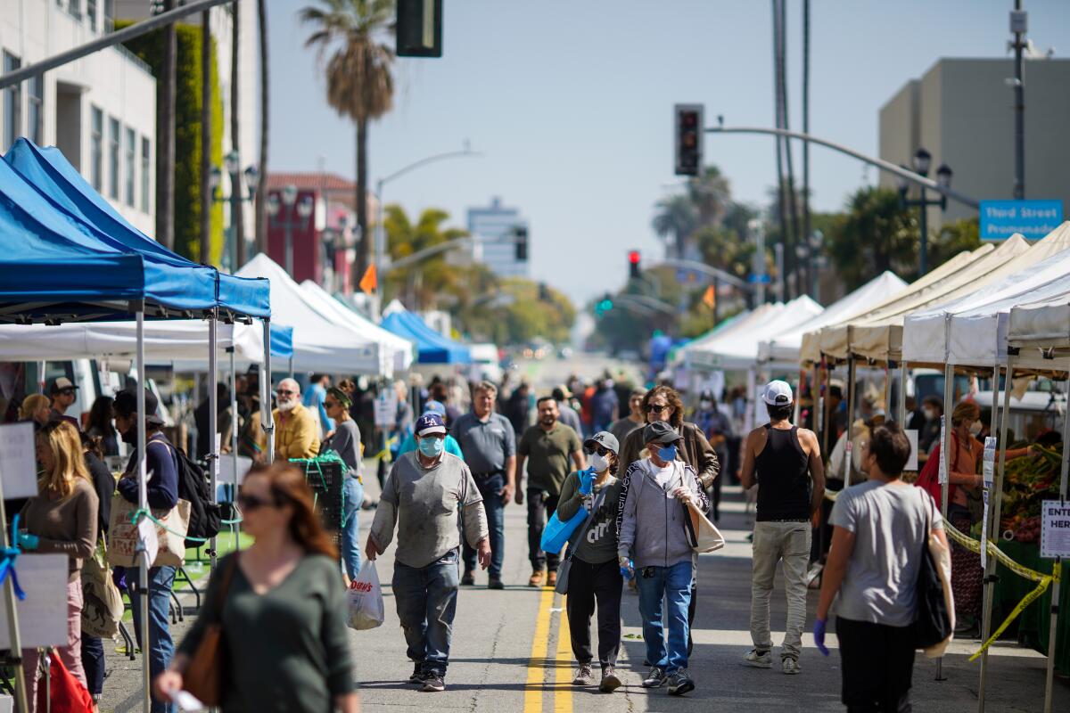People wearing personal protective equipment shop at the Santa Monica Farmers Market on April 1.