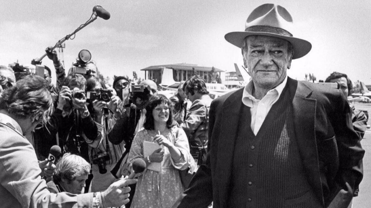 John Wayne chats with newsmen at Orange County Airport in 1978. (Los Angeles Times)
