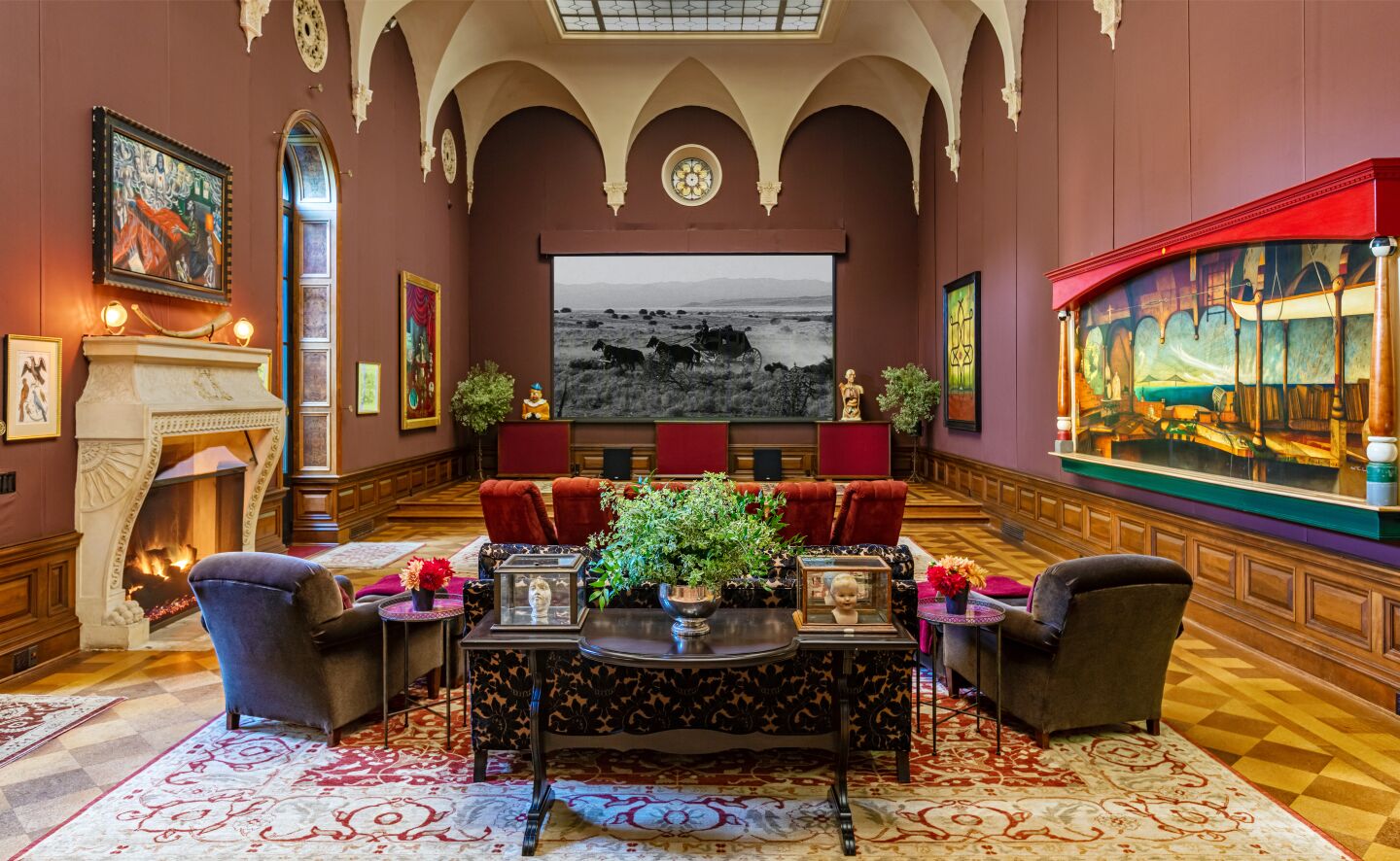 The ballroom with living room furniture, a fireplace, high ceiling, colorful art, rug, and moving screening area.