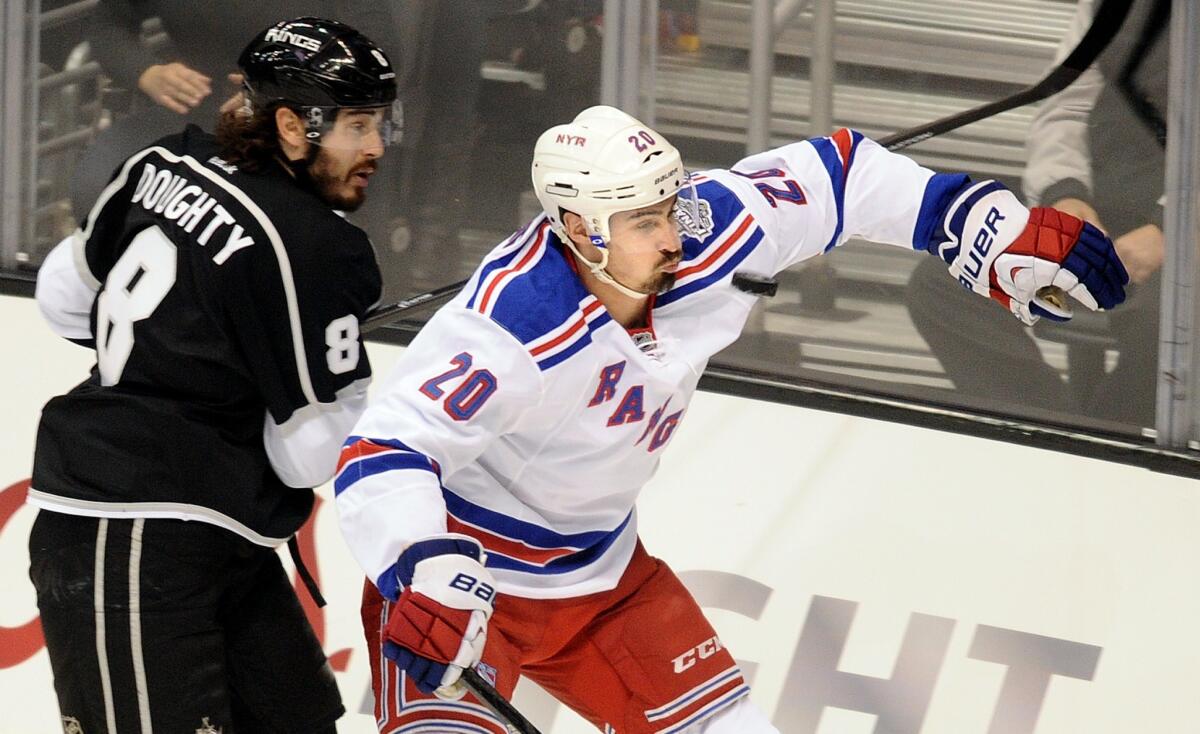 New York Rangers forward Chris Kreider, right, takes a puck to the face in front of Kings defenseman Drew Doughty during the first period of Game 1 of the Stanley Cup Final at Staples Center.