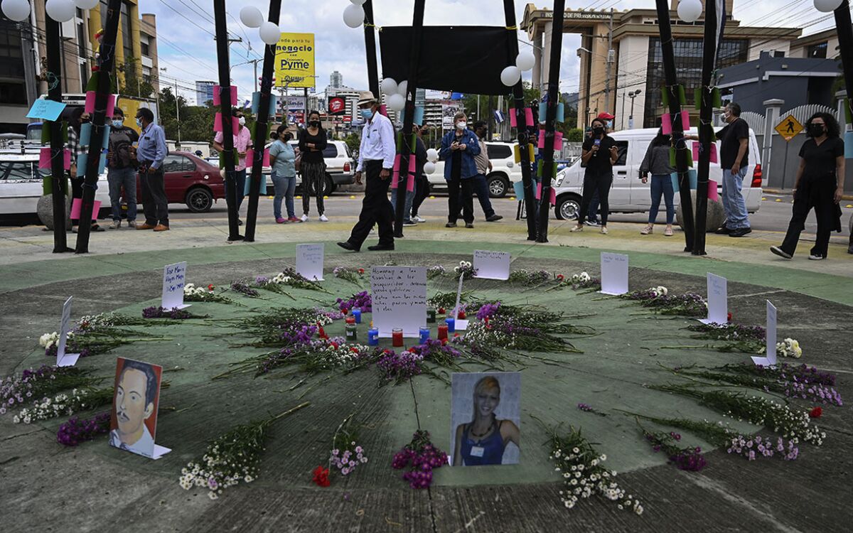 A street memorial with flowers and pictures of victims of political violence arranged in a circle