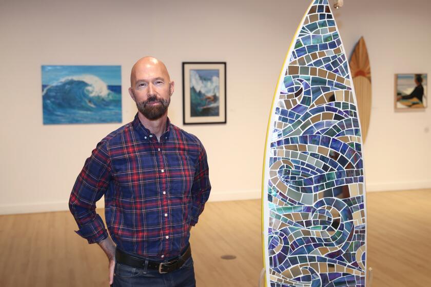 Dan Faltz, new senior supervisor, stands in front of a mozaic surfboard in main showroom at his first show, Surf City Art, at Huntington Beach Art Center.