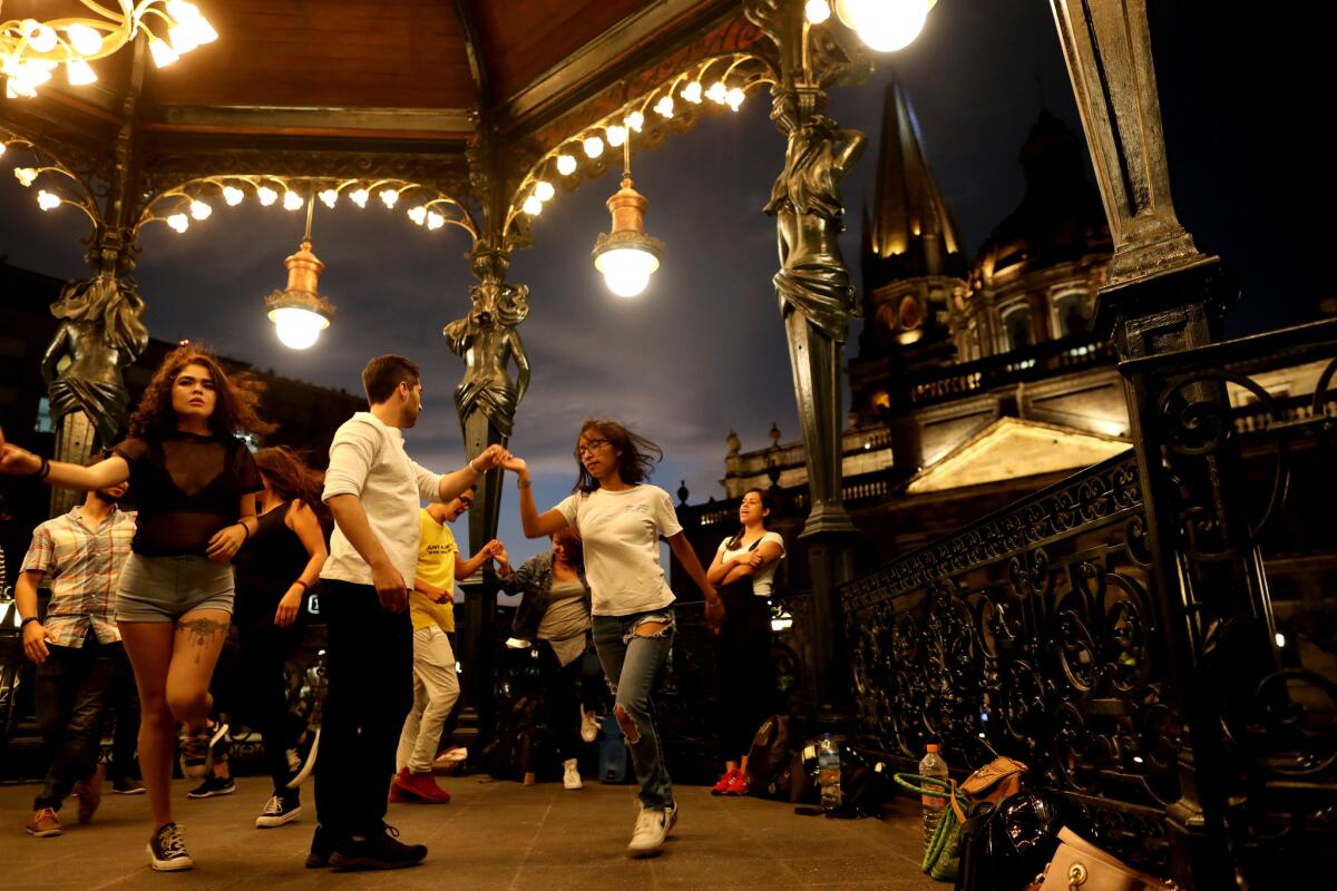 People take a dance lesson in the Plaza de Armas with the Cathedral of the Assumption of Our Lady, right, Roman Catholic cathedral, in the background in Guadalajara. (Gary Coronado / Los Angeles Times)