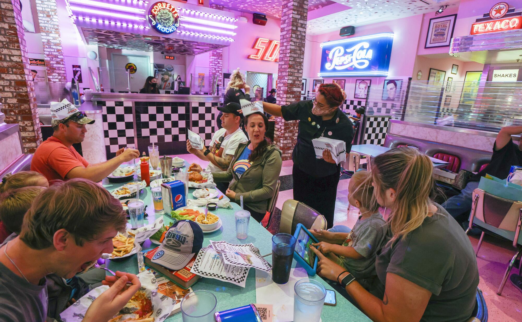 A server passes out hats last month at Corvette Diner in Liberty Station.