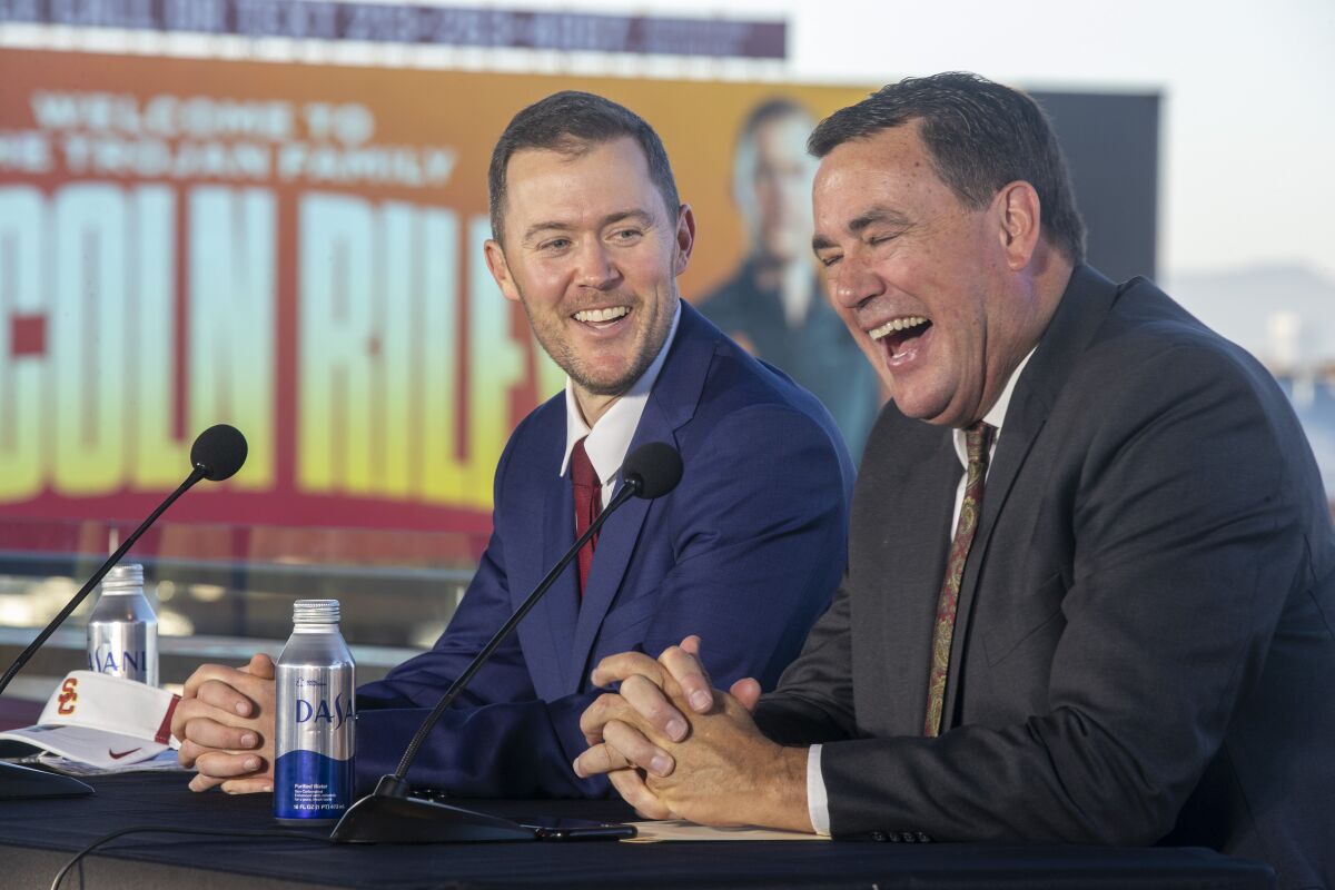 USC atletizm direktörü Mike Bohn ve futbol koçu Lincoln Riley, Coliseum'da düzenlenen bir basın toplantısında gülüyorlar.