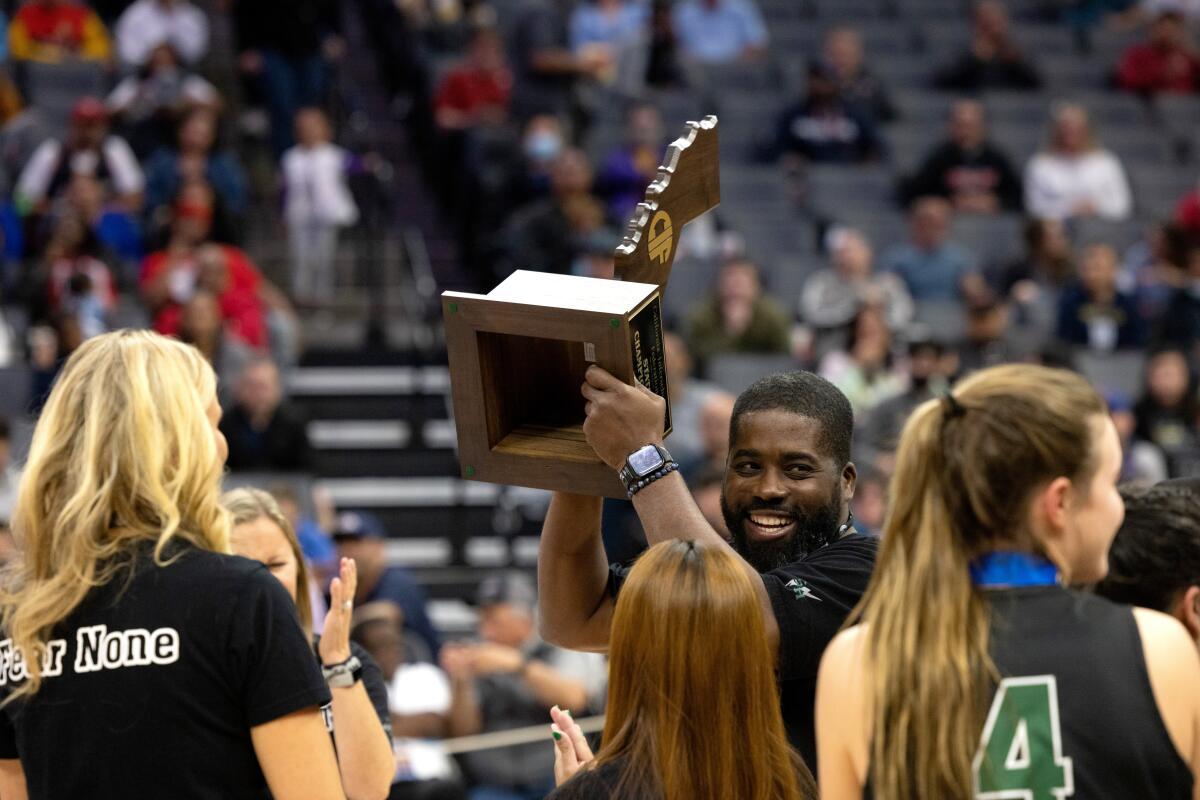 Sage Hill girls' basketball coach Kerwin Walters hoists the CIF State Division II championship trophy.