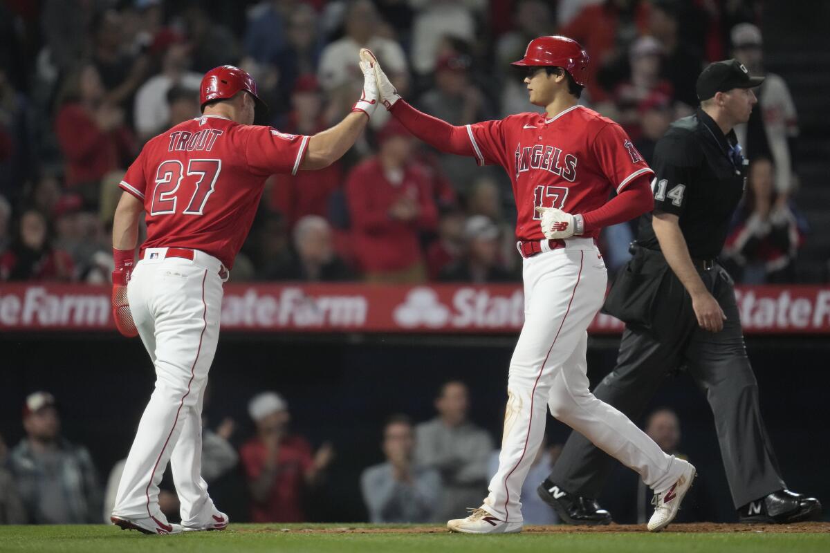 Angels' Mike Trout high-fives designated hitter Shohei Ohtani after they both scored off of a double hit by Anthony Rendon.