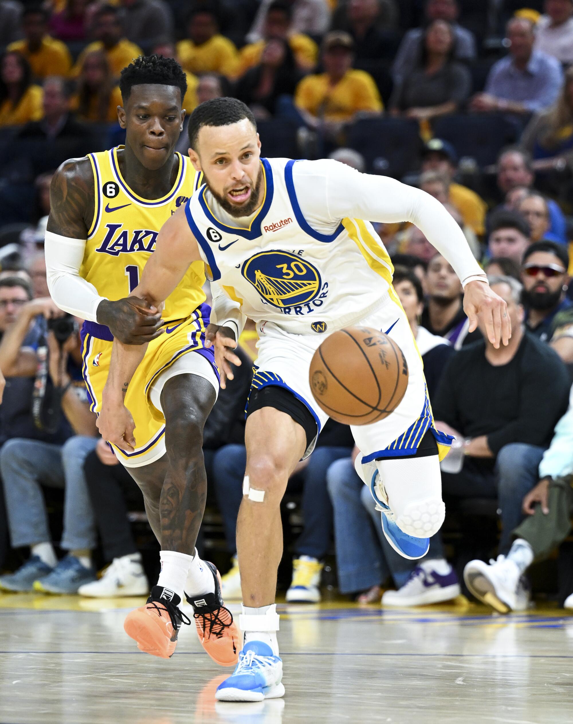 Lakers guard Dennis Schroder grabs the arm of Warriors guard Stephen Curry while chasing a loose ball.