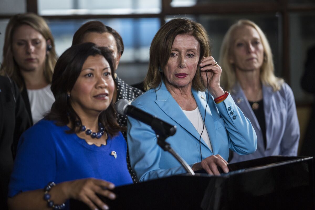 House Speaker Nancy Pelosi listens to Rep. Norma Torres speak at a news conference in Guatemala City.