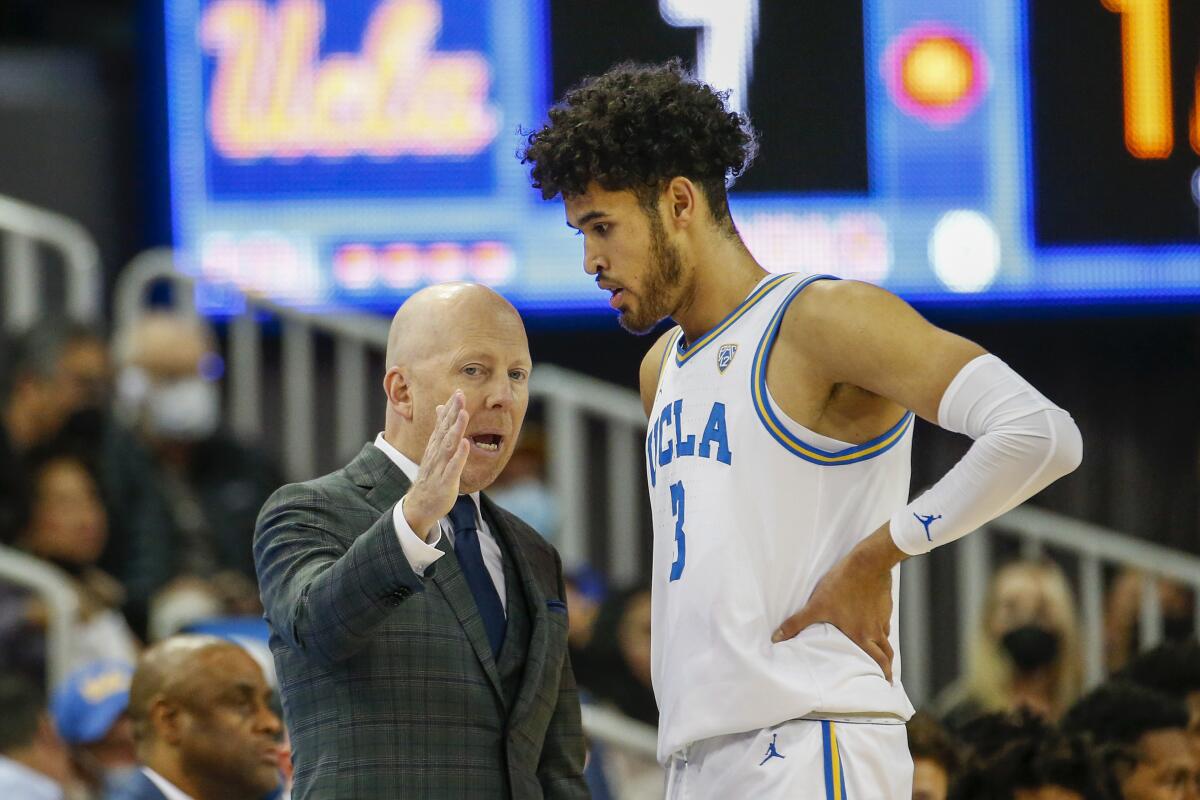 UCLA coach Mick Cronin, left, confers with guard Johnny Juzang.