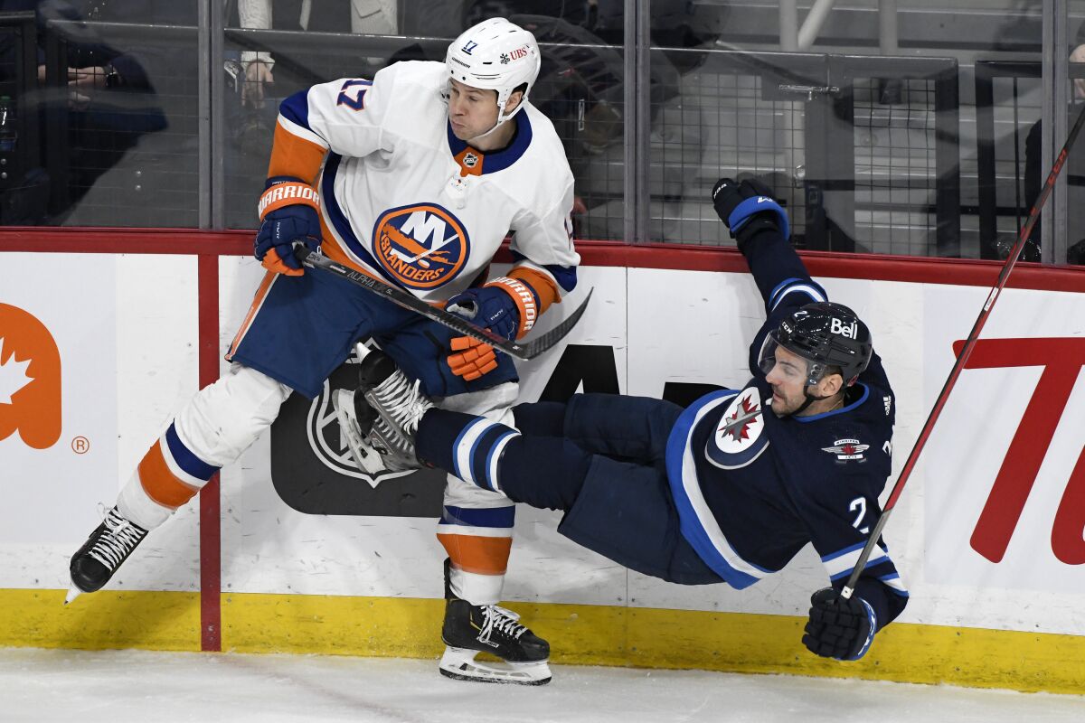 Winnipeg Jets' Dylan DeMelo (2) is checked by New York Islanders' Matt Martin (17) during the first period of NHL hockey game action in Winnipeg, Manitoba, Saturday, Nov. 6, 2021. (Fred Greenslade/The Canadian Press via AP)