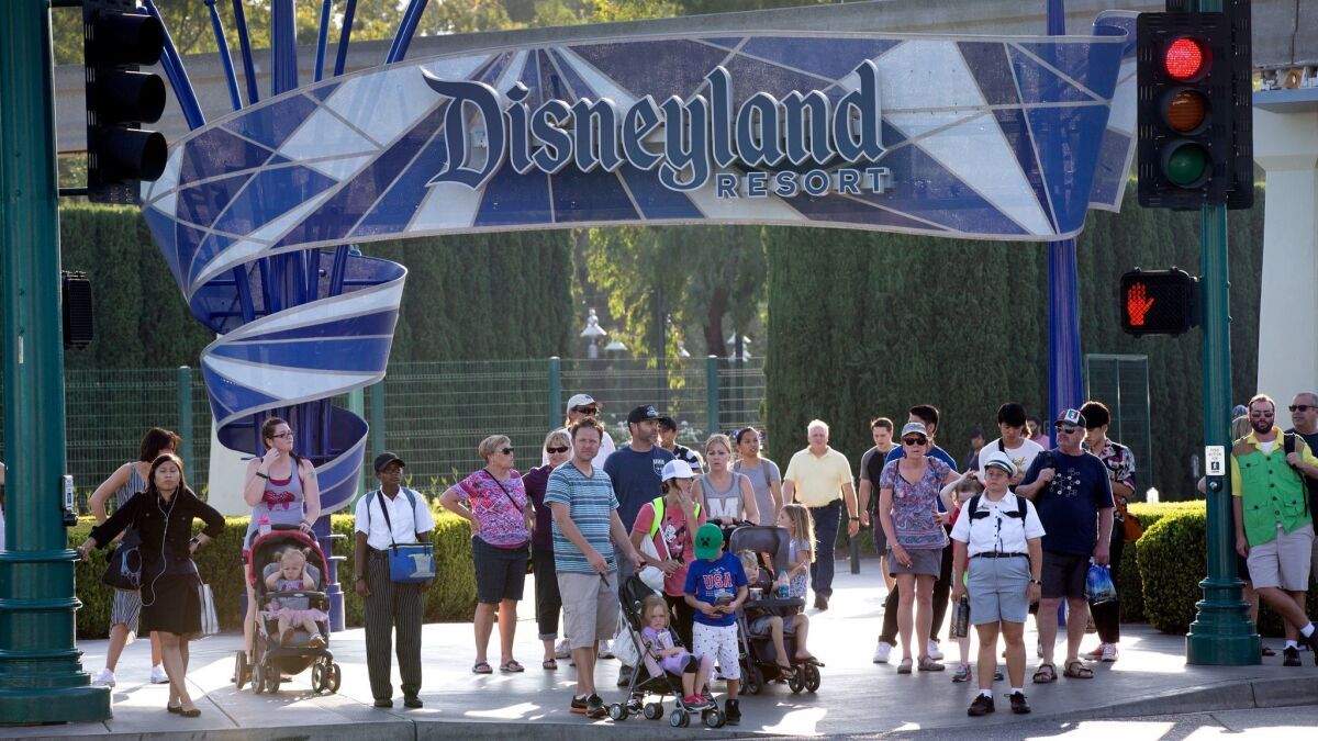 Disneyland patrons exit the park under the Disneyland sign at a shuttle area in Anaheim in 2017. A proposed city ordinance would require the resort to raise hourly wages for its workers.