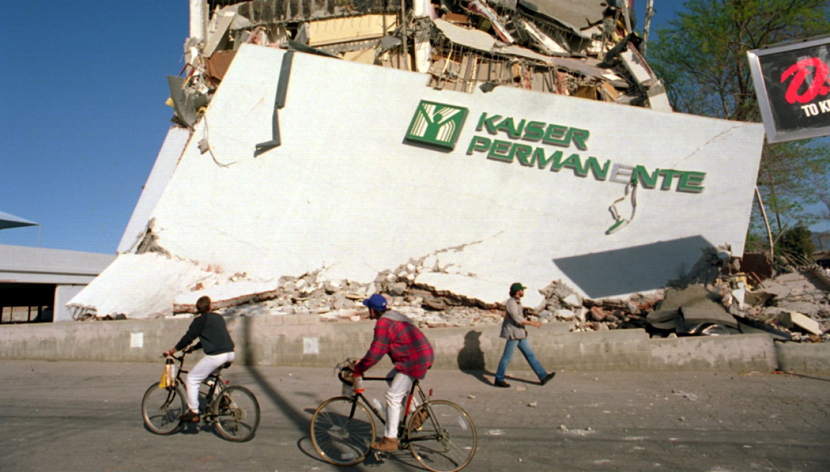 Cyclists roll past the remains of a collapsed Kaiser Permanente clinic and office building in Granada Hills.