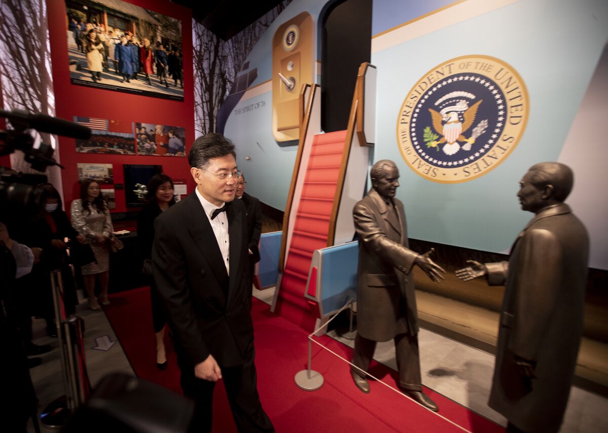 Ambassador walks past statues of Nixon greeting the Chinese premier in front of a miniature replica of Air Force One