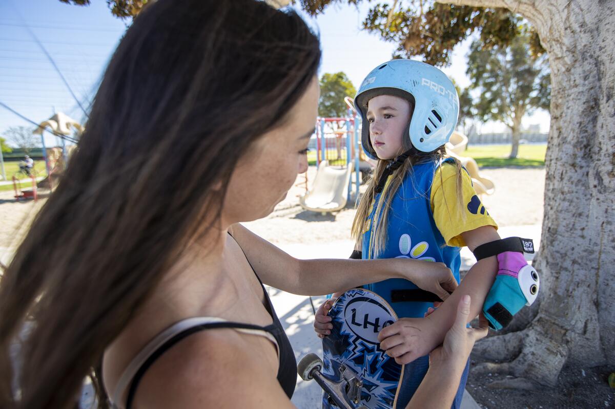 Ruth Benton helps her daughter Brooke, 6, with her elbow pads before a session at Edison Park Skate Spot on Wednesday.