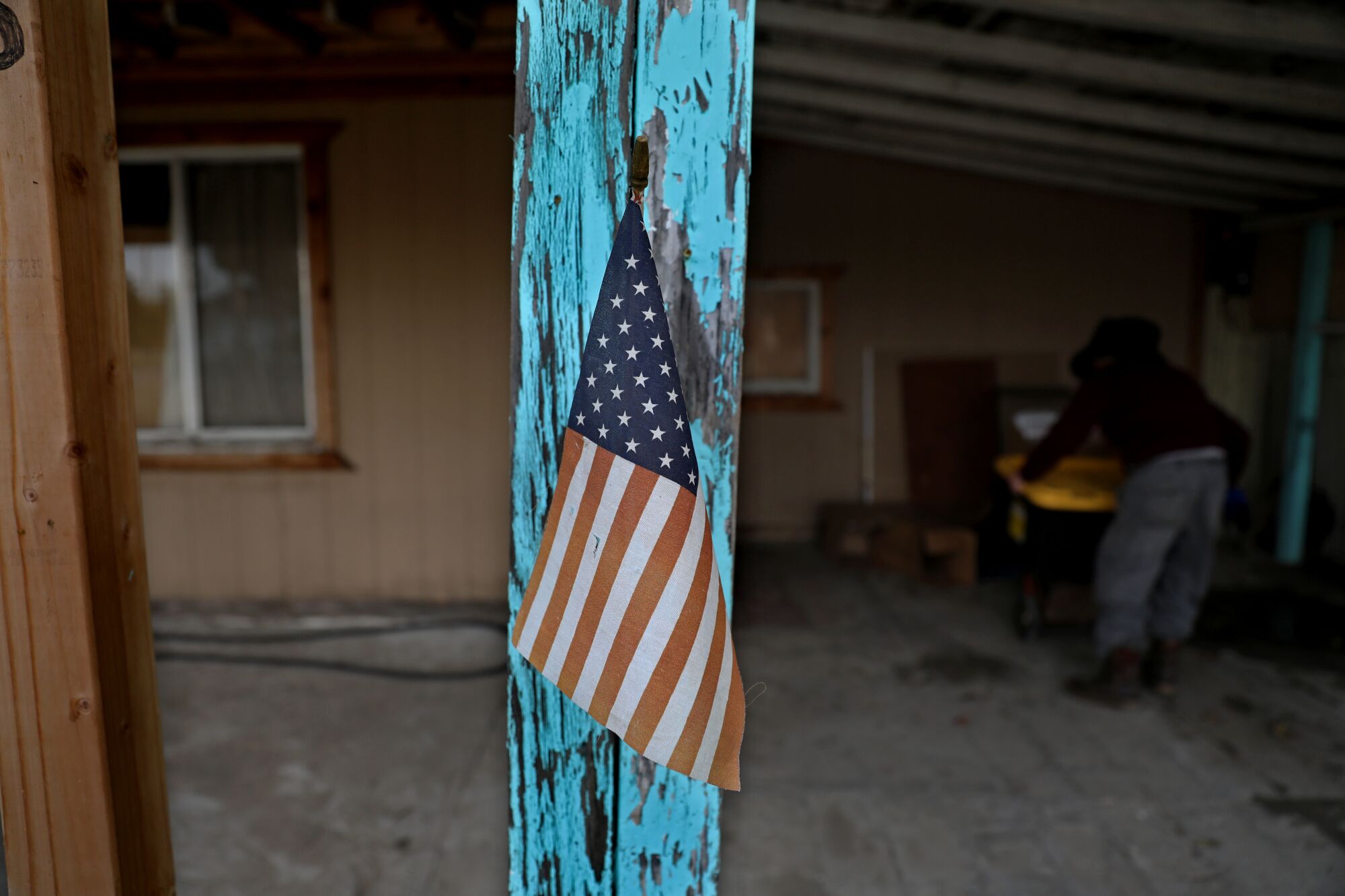 An American flag is planted on a faded blue beam on a home in Planada, Calif.