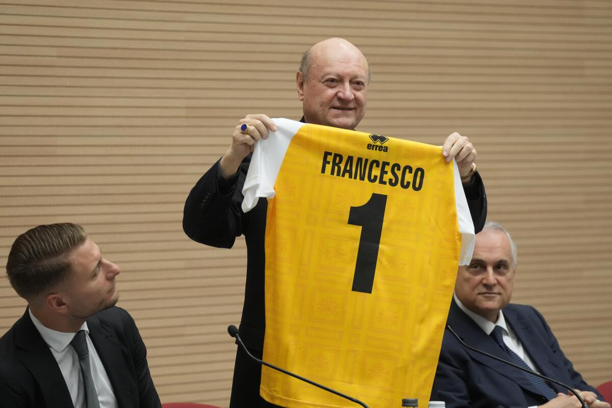 Cardinal Gianfranco Ravasi shows to journalists the jersey of the Vatican soccer team which will be donated to Pope Francis as he presents the soccer match between the Vatican soccer team "Fratelli Tutti" (All Brothers) and the World Rom Organization team, at the Vatican, Tuesday, Nov. 16, 2021. The match will be played Sunday, Nov. 21, at the Lazio training ground of Formello. (AP Photo/Gregorio Borgia)