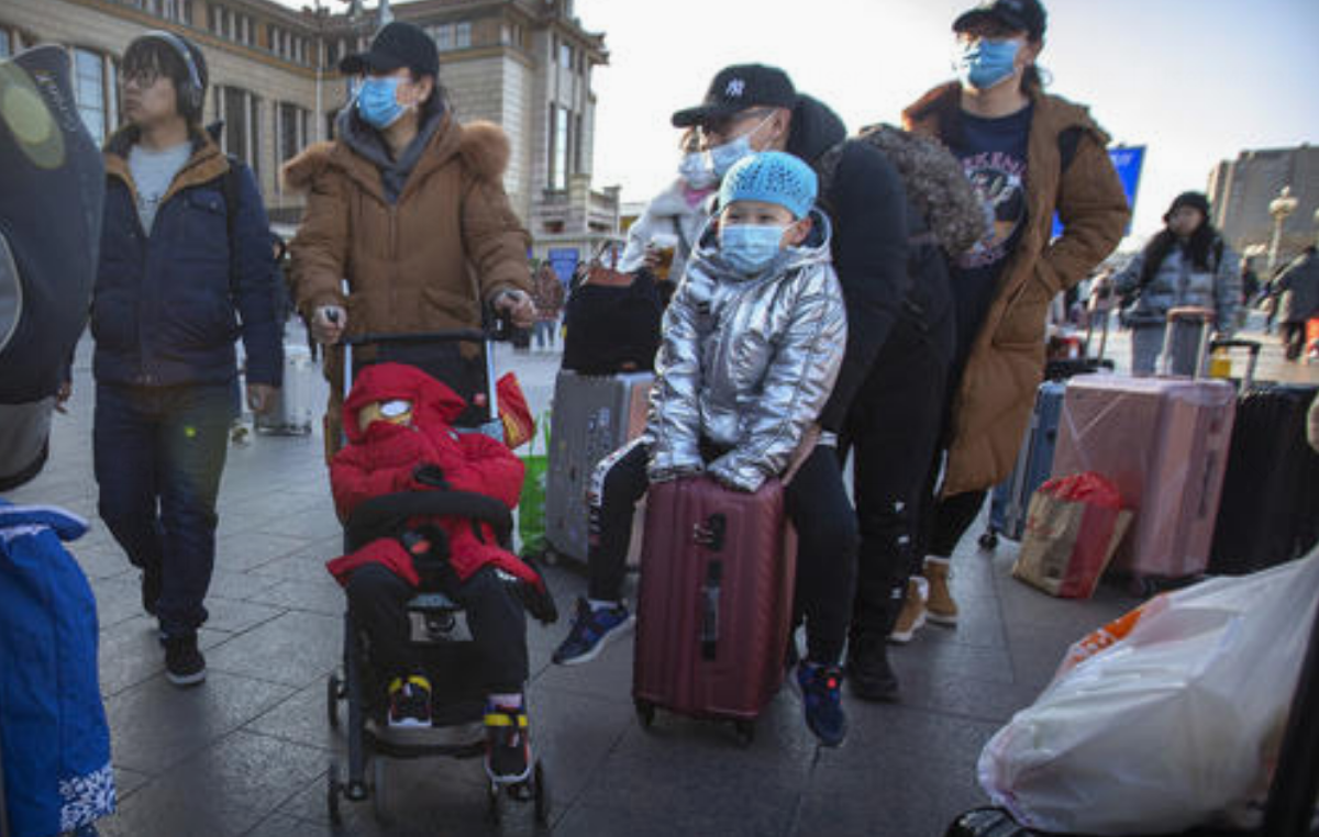 Los viajeros llevan máscaras para la cara cuando salen de la estación de ferrocarril de Pekín, el lunes 20 de enero de 2020.