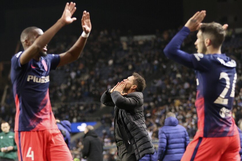 Atletico Madrid head coach Diego Simeone, center, celebrates after Rodrigo De Paul scored their side's third goal, with teammates Angel Correa and Antoine Griezmann in the background, during the Champions League Group B soccer match between FC Porto and Atletico Madrid at the Dragao stadium in Porto, Portugal, Tuesday, Dec. 7, 2021. (AP Photo/Luis Vieira)